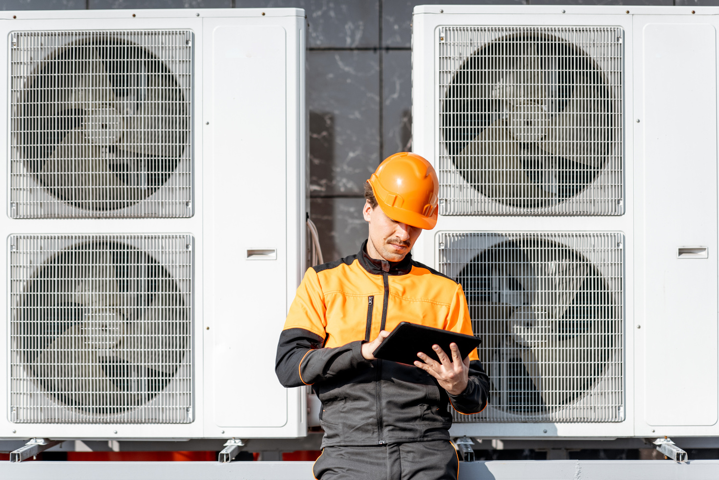 Workman Servicing Air Conditioning or Heat Pump with Digital Tablet
